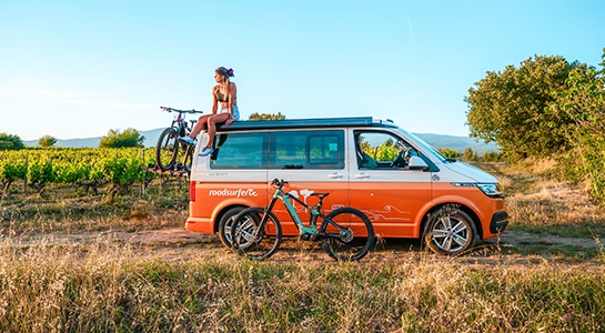 girl sitting on top of an orange campervan