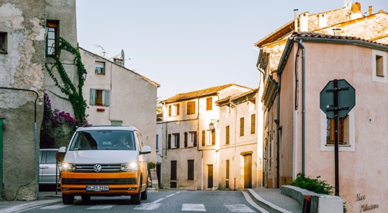 Volkswagen campervan driving through a samll town in France