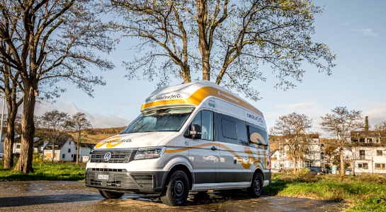 Motorhome is parked in the city under a tree