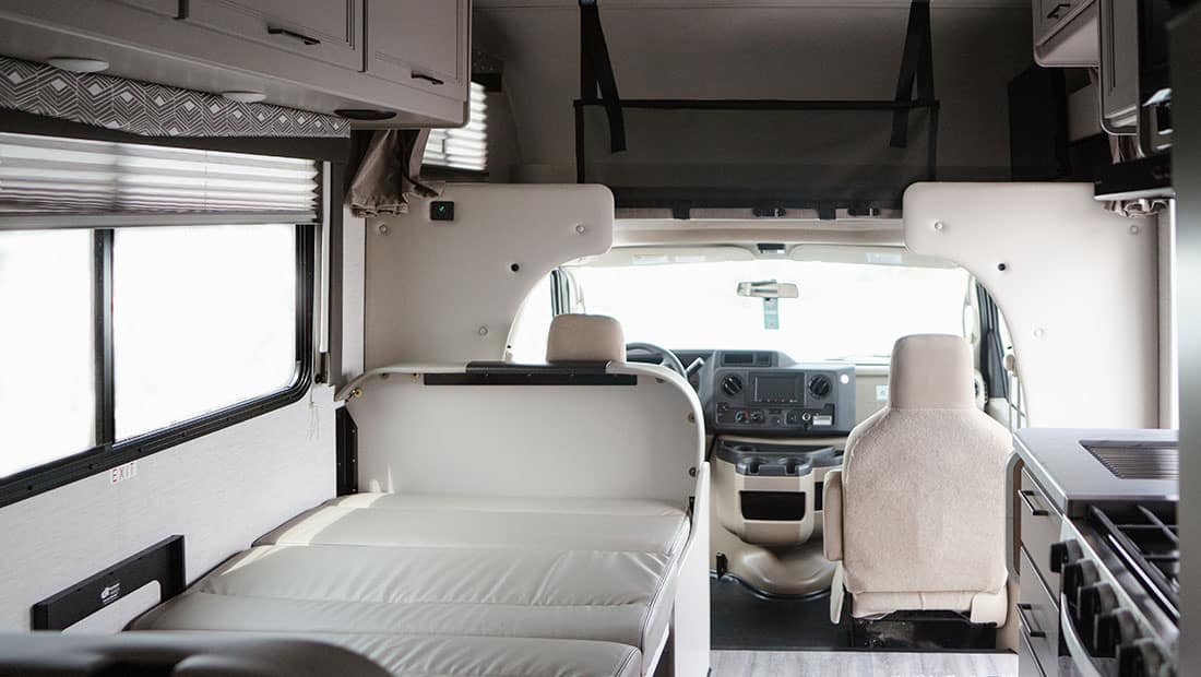 Interior view of an RV motorhome showing a converted bed in the dining area