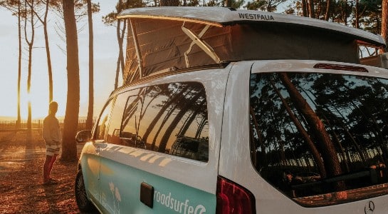 man standing in the sun in front of a campervan