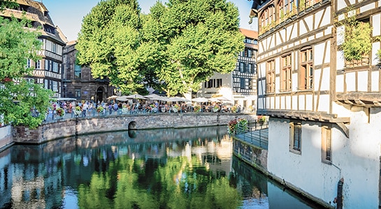 People eating in a restaurant located at a river, which seems to be flowing through town.