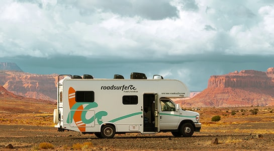 White roadsurfer RV photgraphed in the desert with the Grand Canyon visible in the background.