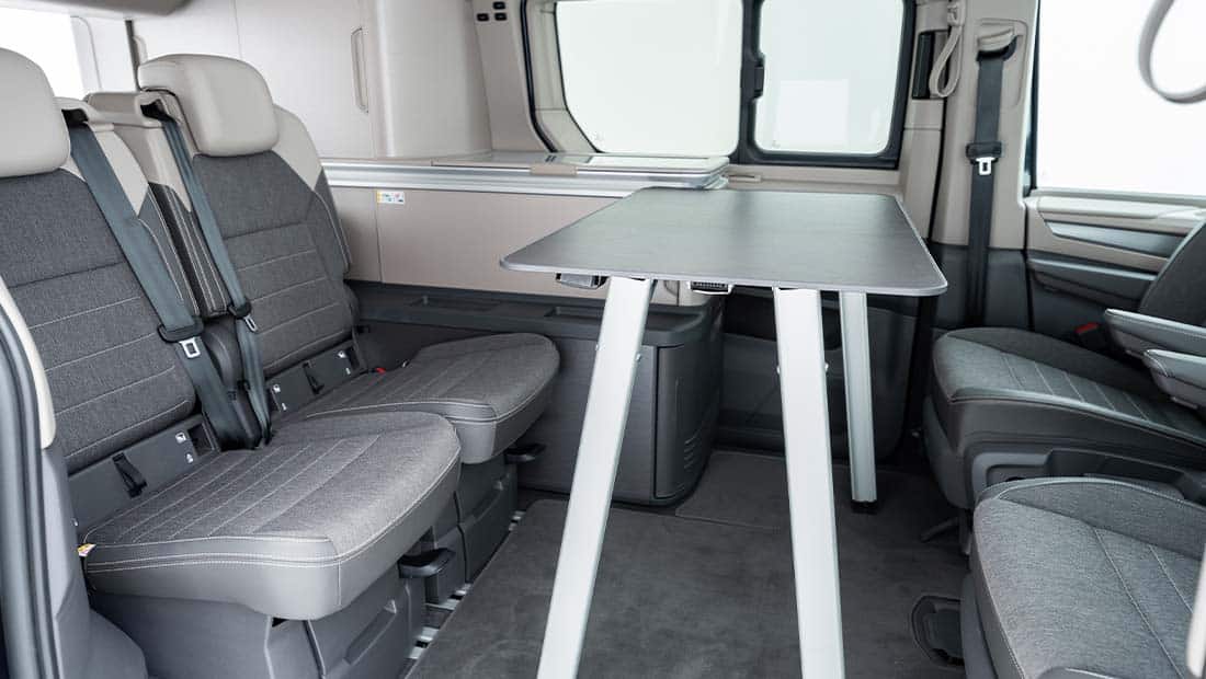 roadsurfer Sunrise Suite interior view showing the seating area from the side with the indoor table