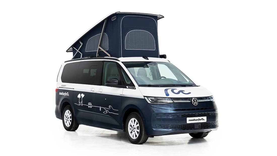 new vw california ocean as roadsurfer campervan sunrise suite in dark blue slanted view with pop up roof open