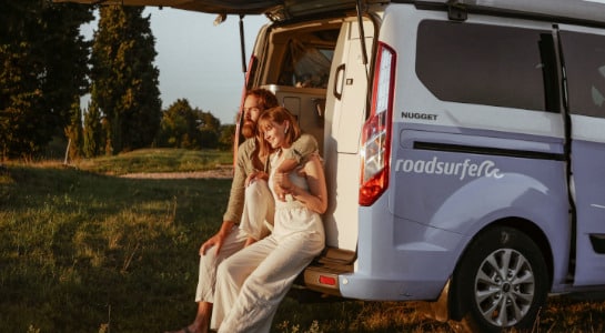 Couple sitting in the back of a VW California enjoying the sunshine