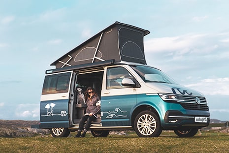Woman sits with dog in her campervan